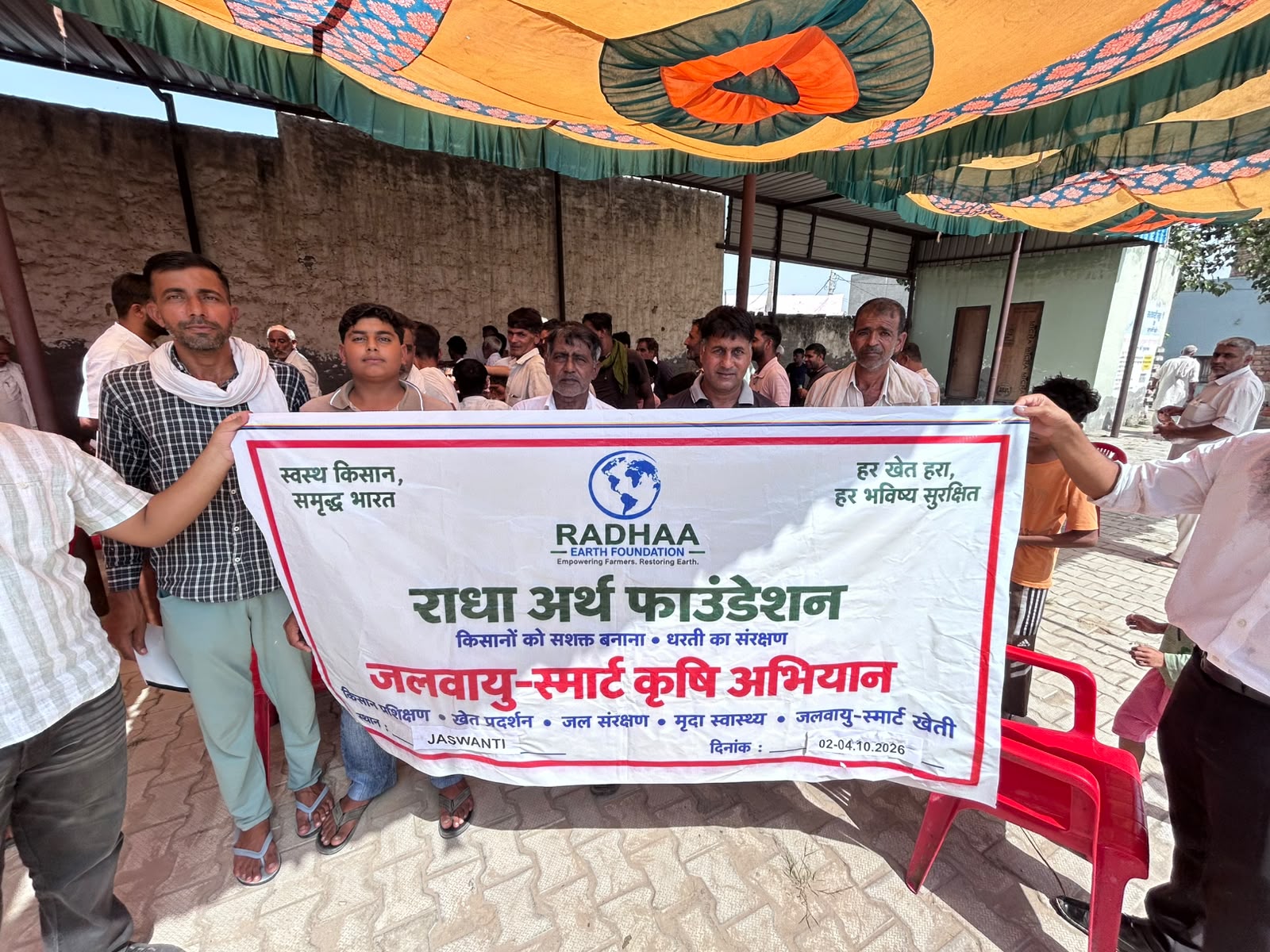 Community members standing behind the RADHAA climate-smart agriculture campaign banner