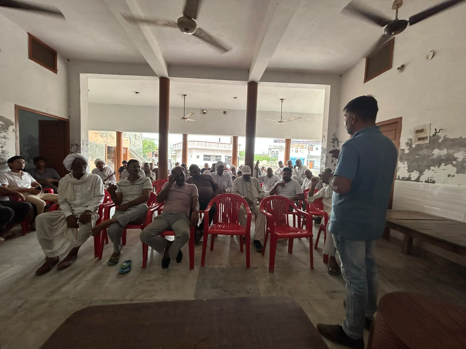 A facilitator speaking with farmers during an indoor training session